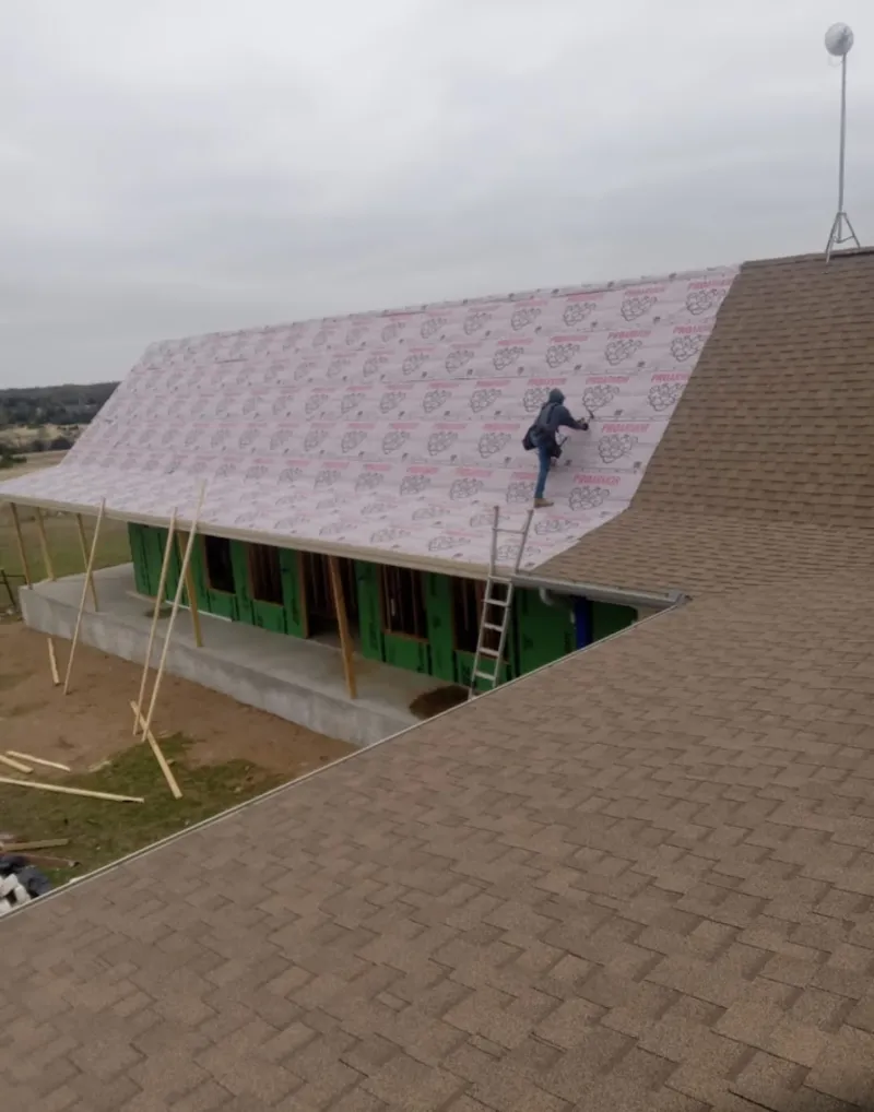 Worker preparing underlayment for a metal roof installation in Noblesville